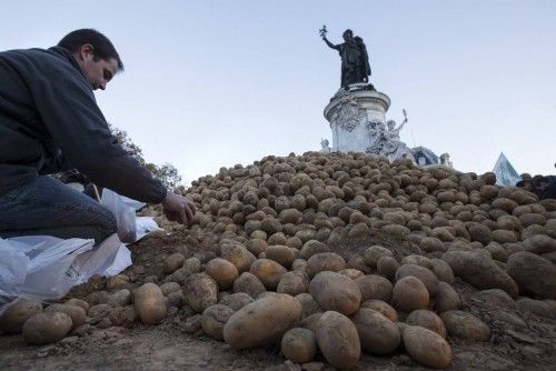 A farmer puts potatoes in bags before a distribution at Republique square in central Paris