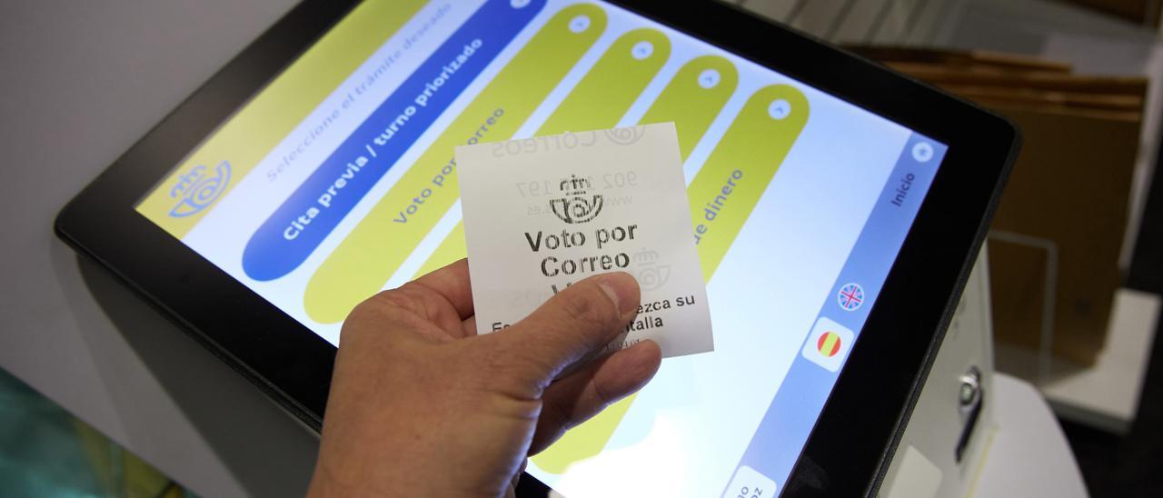 Una persona con un ticket de voto por correo en la oficina de Correos.