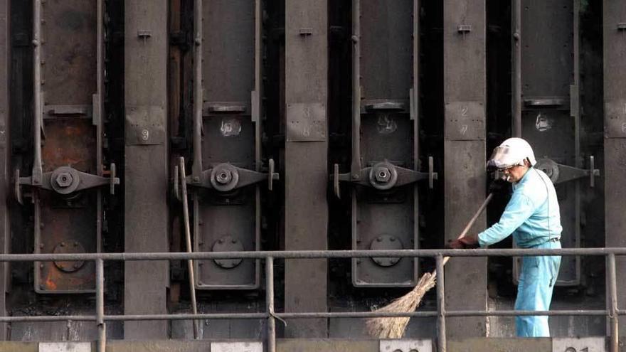 Un operario limpiando el exterior de los hornos de las baterías de coque de Avilés.