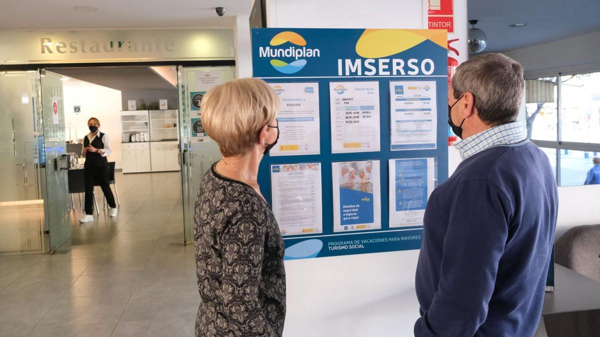 Una pareja de jubilados consulta ayer la programación del Imserso en el tablón de anuncios del hotel Golden de Benidorm. | ÁXEL ÁLVAREZ