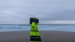 Un hombre carga un cubo lleno de pellets, en la playa Do Dique, a 13 de enero de 2024, en Queiruga, A Coruña, Galicia (España). La conocida ya como la “marea blanca”, se prevé que proceda de los seis contenedores del buque Toconao que cayeron al mar en ag