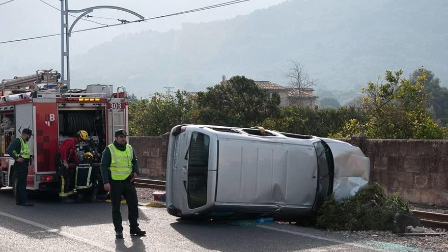 Agentes de la Guardia Civil y bomberos, junto al coche volcado en las vías del tranvía de Sóller.