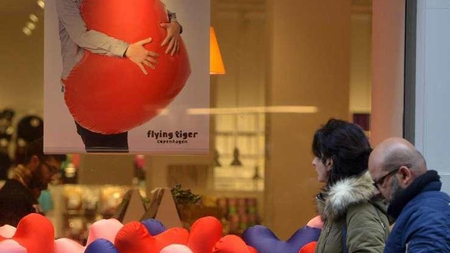 Una pareja pasa frente a un escaparate decorado para San Valentín.