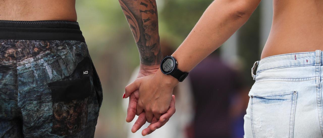 Dos jóvenes caminan agarrados de la mano por la calle.