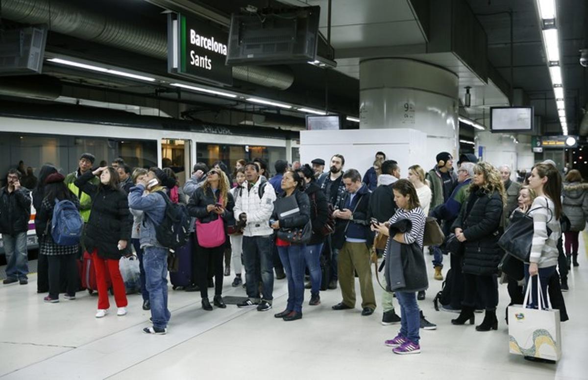 Un grupo de viajeros observa los paneles informativos en la estación de Sants de Barcelona.