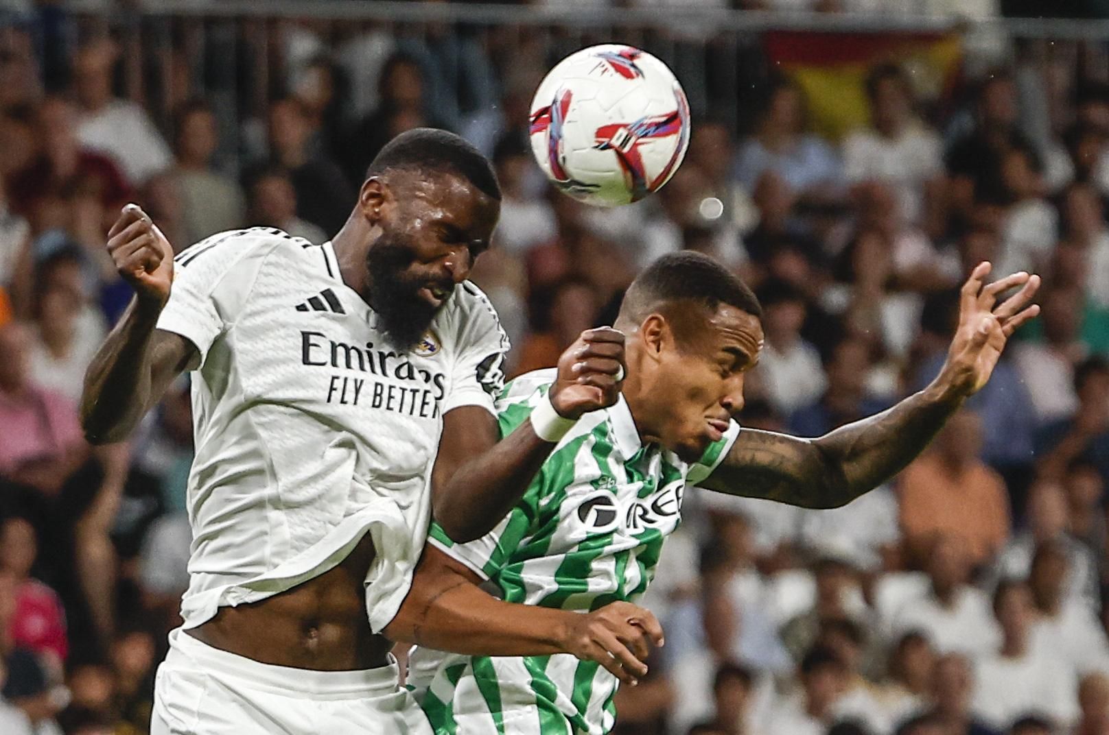 MADRID, 01/09/2024.- El defensa del Real Madrid Antonio Rudiger (i) salta por el balón con Natan Bernardo de Souza, del Betis, durante el partido de la cuarta jornada de LaLiga entre el Real Madrid y el Real Betis, este domingo en el estadio Santiago Bernabéu. EFE/Sergio Pérez