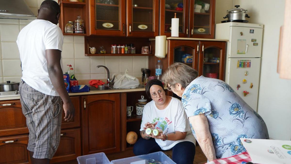 Dos voluntarios de la Fundación escribano llevan comida a una mujer mayor.