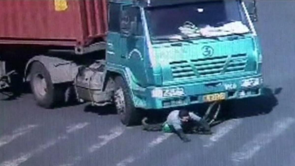 Un motorista xinès surt il·lès després de passar-li per sobre un camió de gran tonatge.