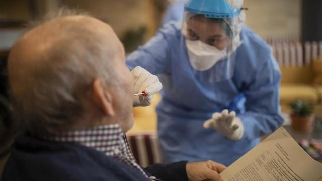 Una voluntaria de Open Arms realiza un test de detección de coronavirus a un anciano en una residencia de Barcelona.