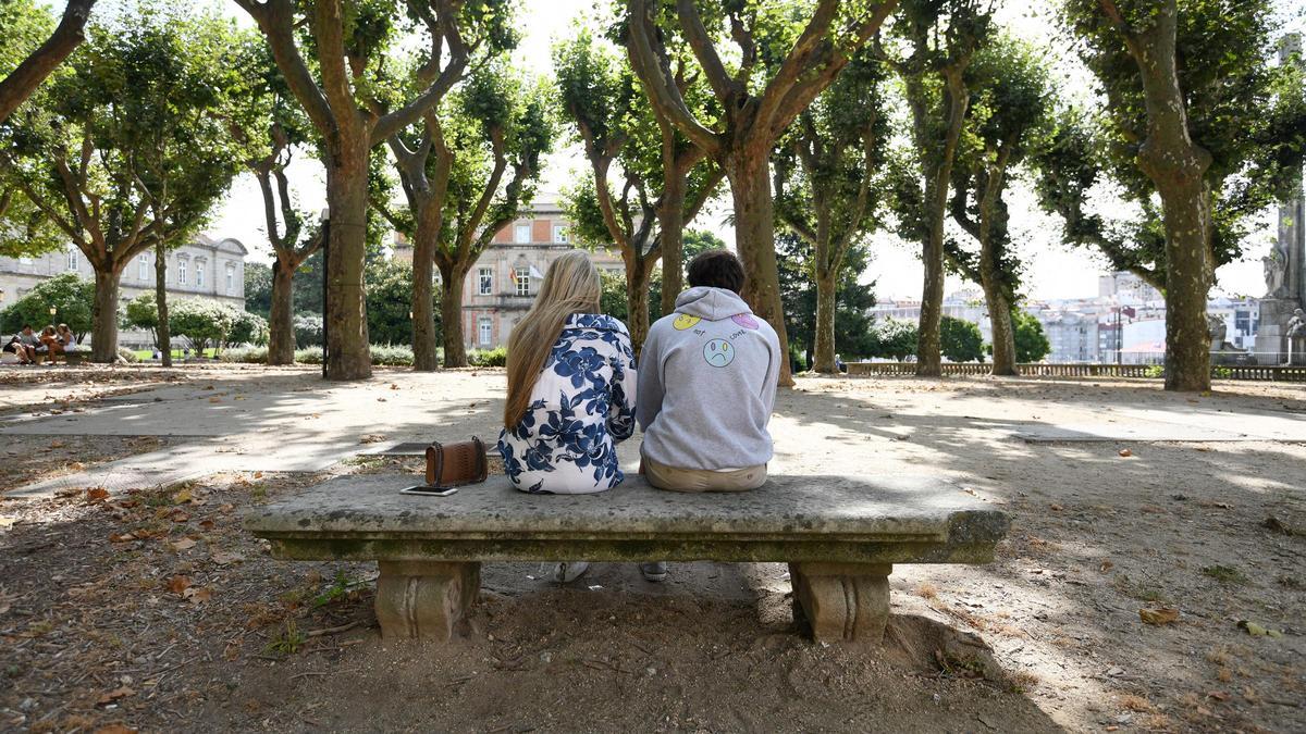 Una pareja de jóvenes, sentados de espaldas.