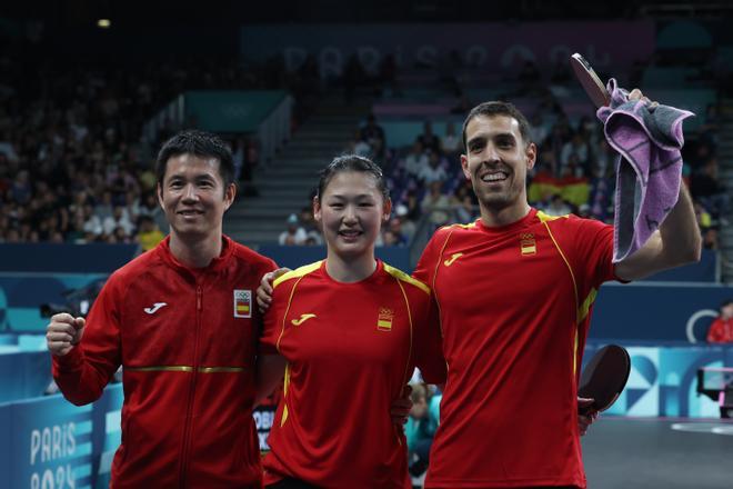 La pareja española, María Xiao (c) y Álvaro Robles, junto a su entrenador, Shi Tian Weidong (i) tras vencer a la pareja brasileña compuesta por Vitor Ishiy y Bruna Takahashi, al finalizar el partido de Octavos de Final de Dobles Mixto de Tenis de Mesa, en los Juegos Olímpicos de París 2024.