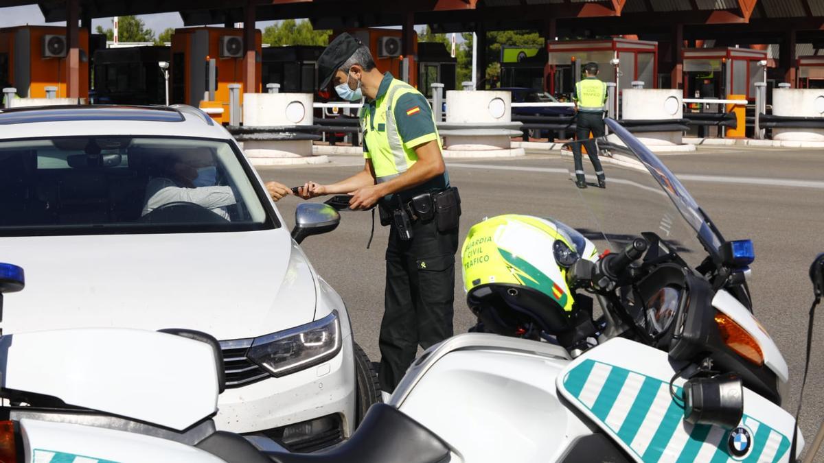 Un agente de la Guardia Civil controla a un conductor, esta mañana, en el peaje de Alagón.