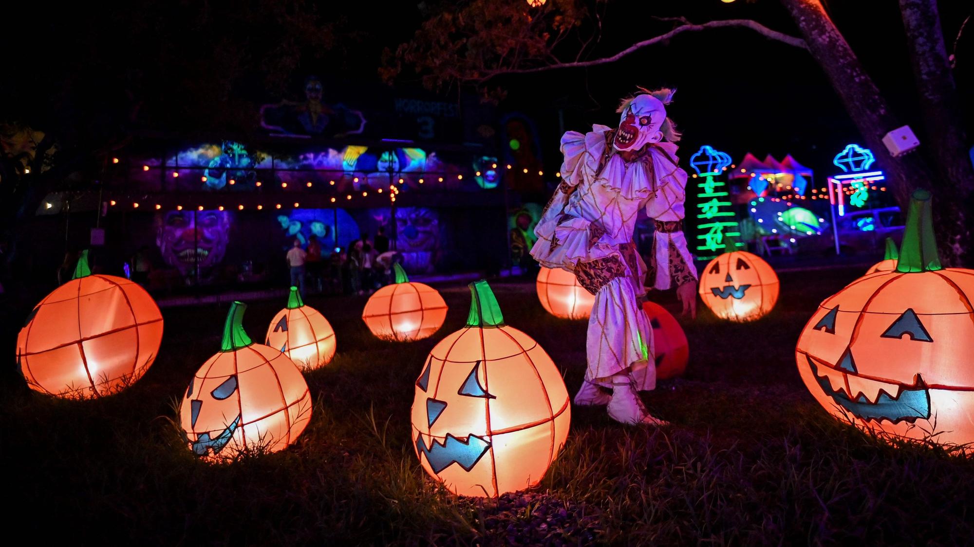 Un hombre usa un disfraz de payaso de pesadilla en medio de Jack O'lanterns durante un espectáculo en River View Park en Cali, Colombia, el 29 de octubre de 2021, antes de Halloween . (Foto de Luis ROBAYO / AFP)