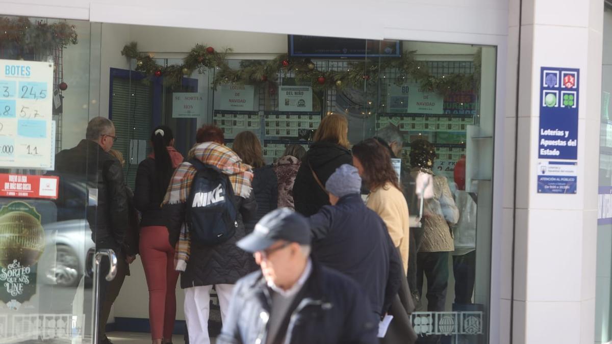 Un grupo de personas hace cola para comprar un décimo de Lotería de Navidad en Alicante, este jueves.