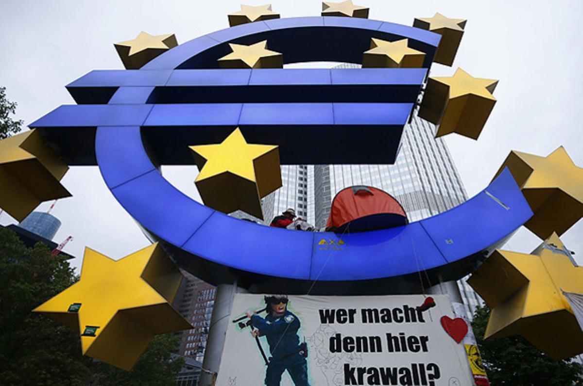 Un manifestant planta la seva tenda al símbol de l’euro durant el desallotjament del campament del moviment dels ’indignats’ davant de la seu del Banc Central Europeu (BCE), a Frankfurt (Alemanya).