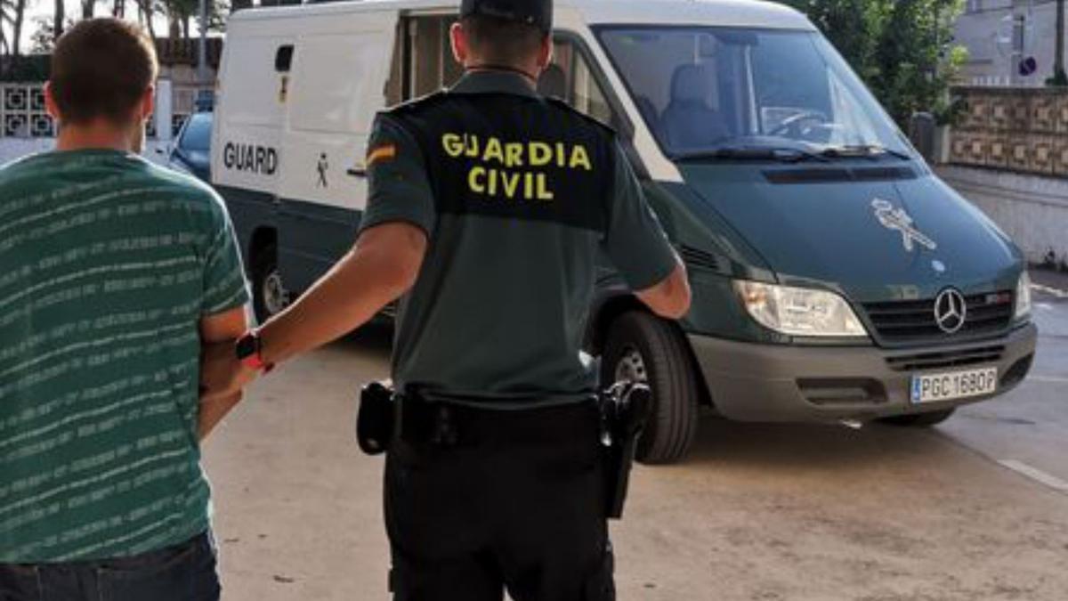 Un agente lleva detenido al ladrón.