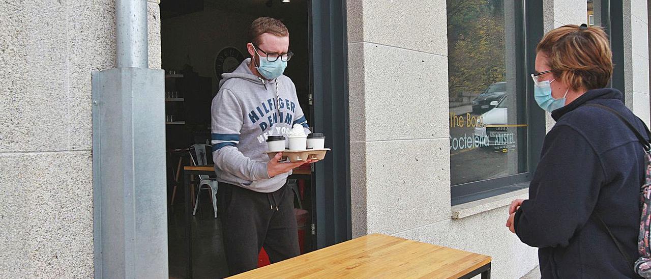 Gabriel Alonso entregando cafés a una clienta que dejó propina en Ribadavia.   | // IÑAKI OSORIO