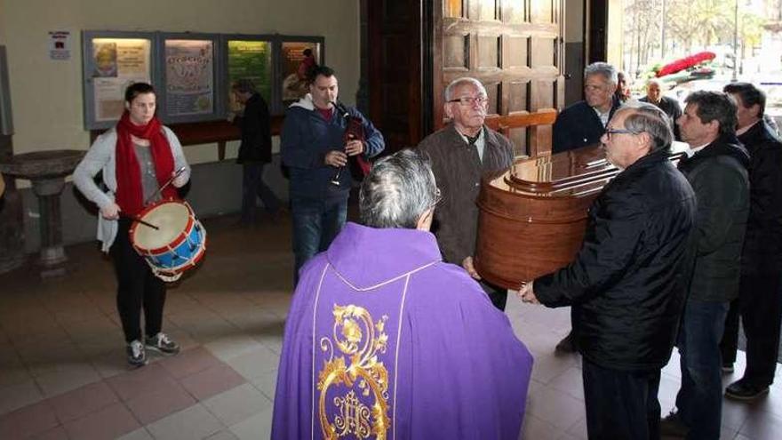 Varias personas introducen el féretro de Erundina Fernández en la iglesia de San Lorenzo a los sones de las gaitas y el tambor.