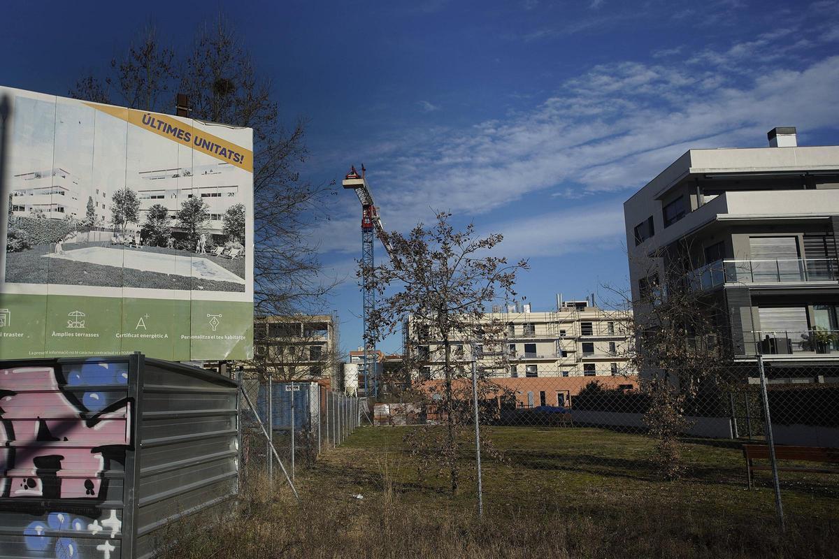 Un cartell que anuncia habitatges en venda a Domeny Sud i, al fons, una grua.