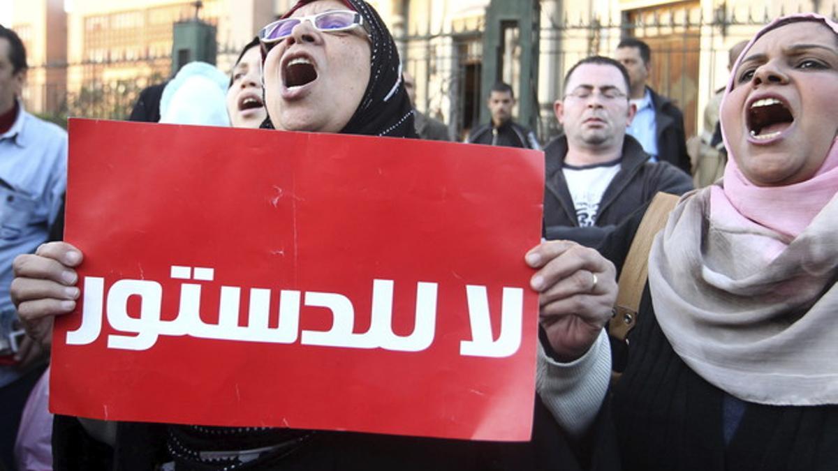 Unas egipcias gritan eslóganes contra Mohamed Mursi y sujetan una pancarta en la que se lee &quot;no a la constitución&quot;