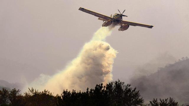 Un avió descarrega aigua sobre un dels incendis a prop de San Martín de Valdeiglesias, a uns 70 quilòmetres de Madrid. | CÉSAR MANSO / AFP