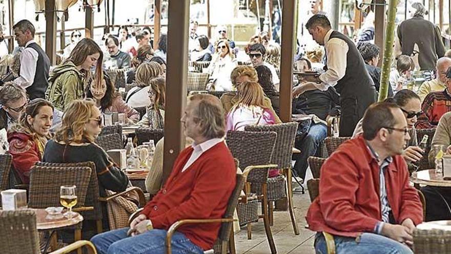 Dos camareros sirven a los clientes en un bar de la plaza Joan Carles I de Palma.