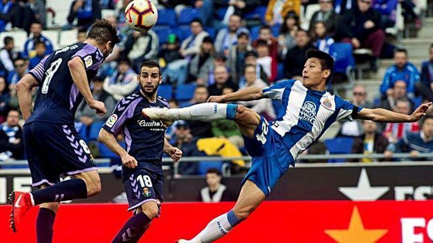 El jugador del Espanyol, Wu Lei, intenta golpear el balón entre dos jugadores del Valladolid.