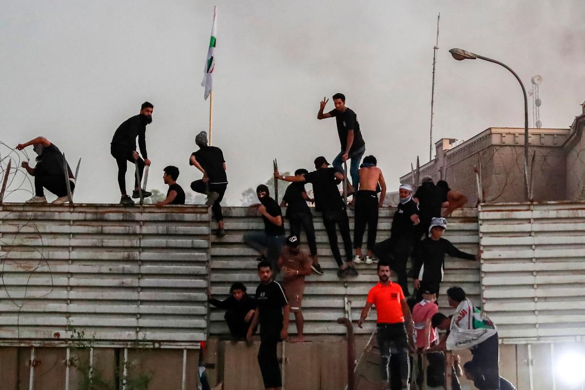 Los partidarios del clérigo chiíta iraquí Moqtada al-Sadr escalan la valla frente a la embajada sueca en Bagdad.