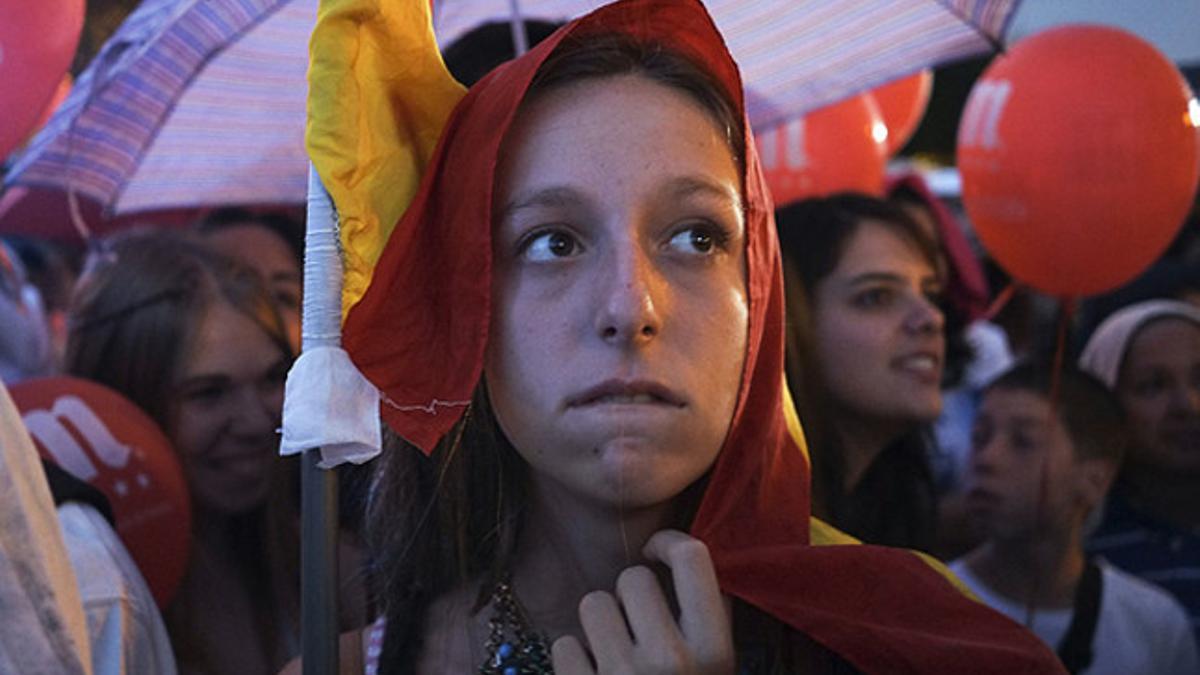 Una chica con la bandera española muestra su decepción en la Puerta de Alcalá.