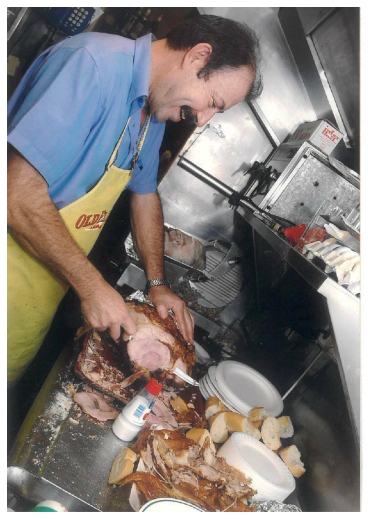 Carmelo García, en 1998, cortando pata asada en la cocina del bodegón.