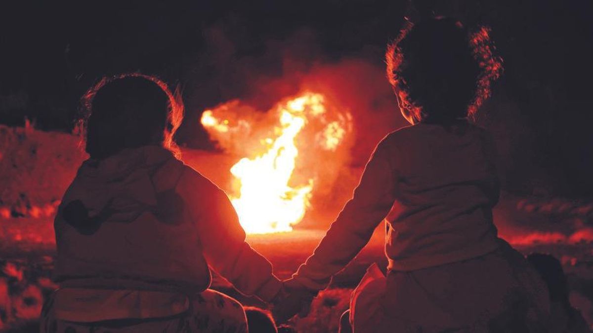 Dos niños contemplan una hoguera de San Juan.