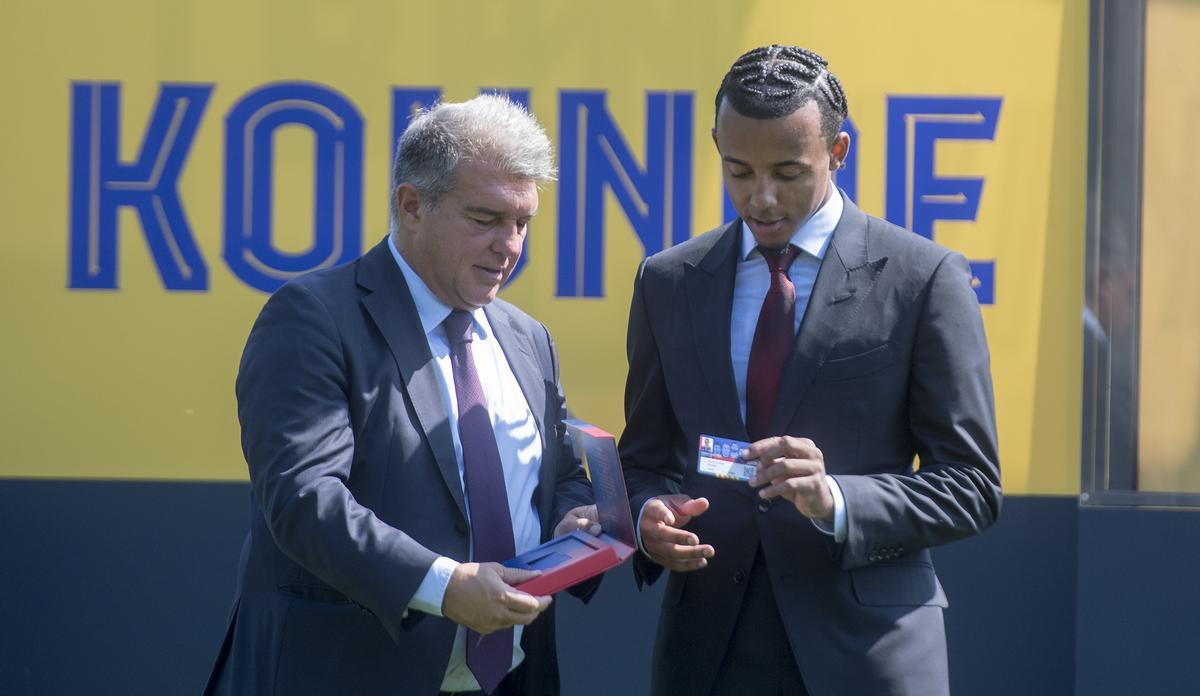 Jules Kounde observa su nuevo carnet de socio culé junto a Joan Laporta.  