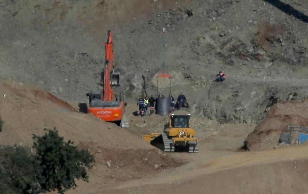 Members of a miner rescue team watch a drilled ...