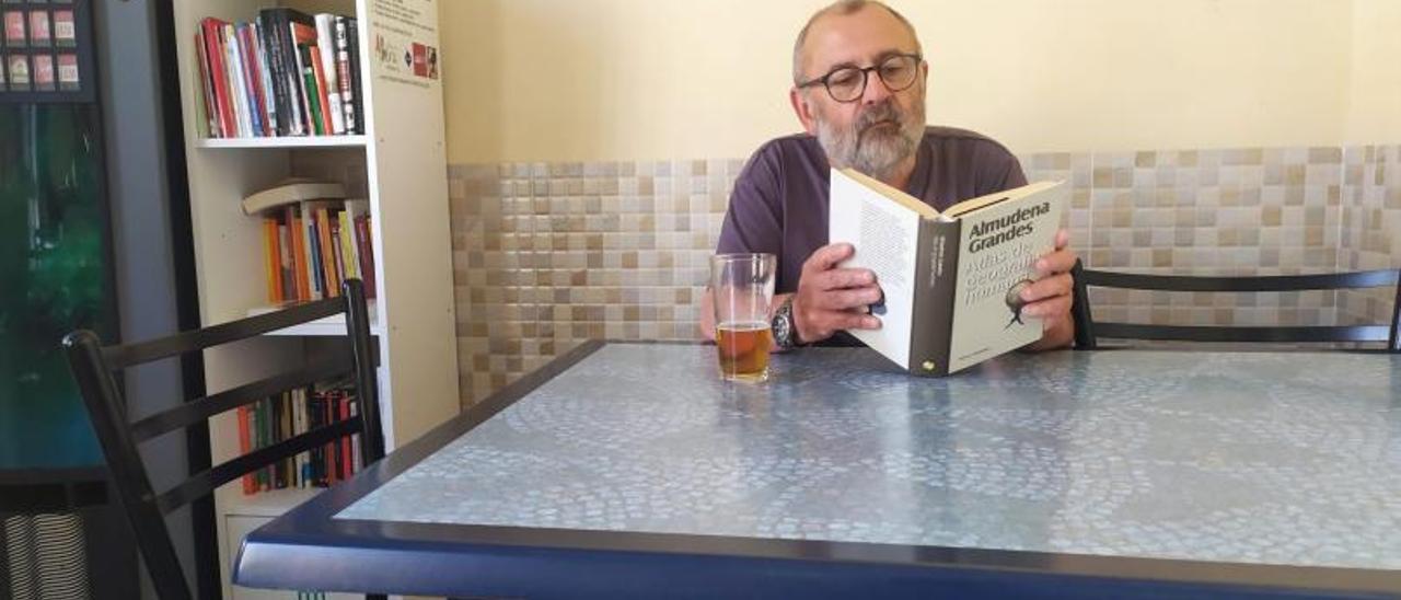Un cliente de un bar ojea una novela junto a la estantería que alberga los libros. | LEVANTE-EMV