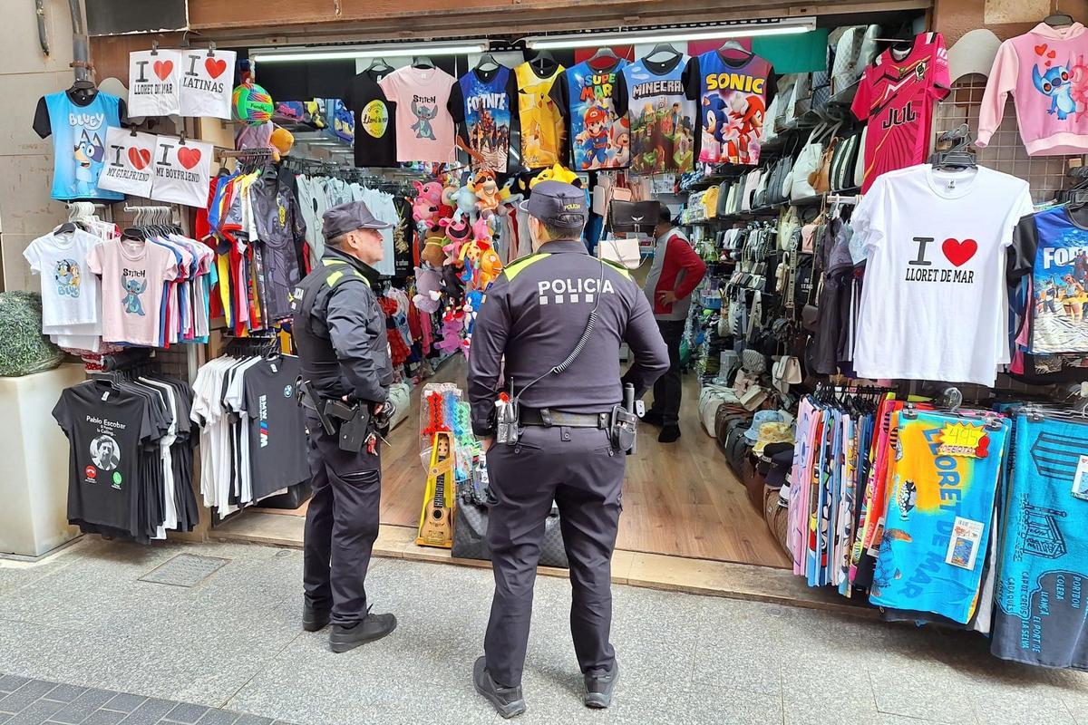 Dos agents de la Policia Local de Lloret de Mar durant la inspecció a la botiga on s'han comissat 500 articles falsificats.