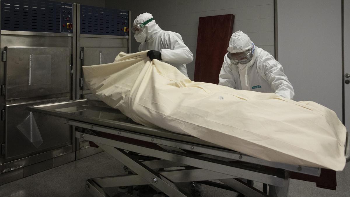Dos operarios de la funeraria de Mataró preparan el entierro de un fallecido por covid.