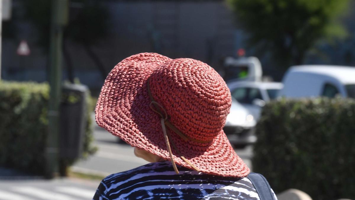 Una mujer con sombrero se protege del sol.