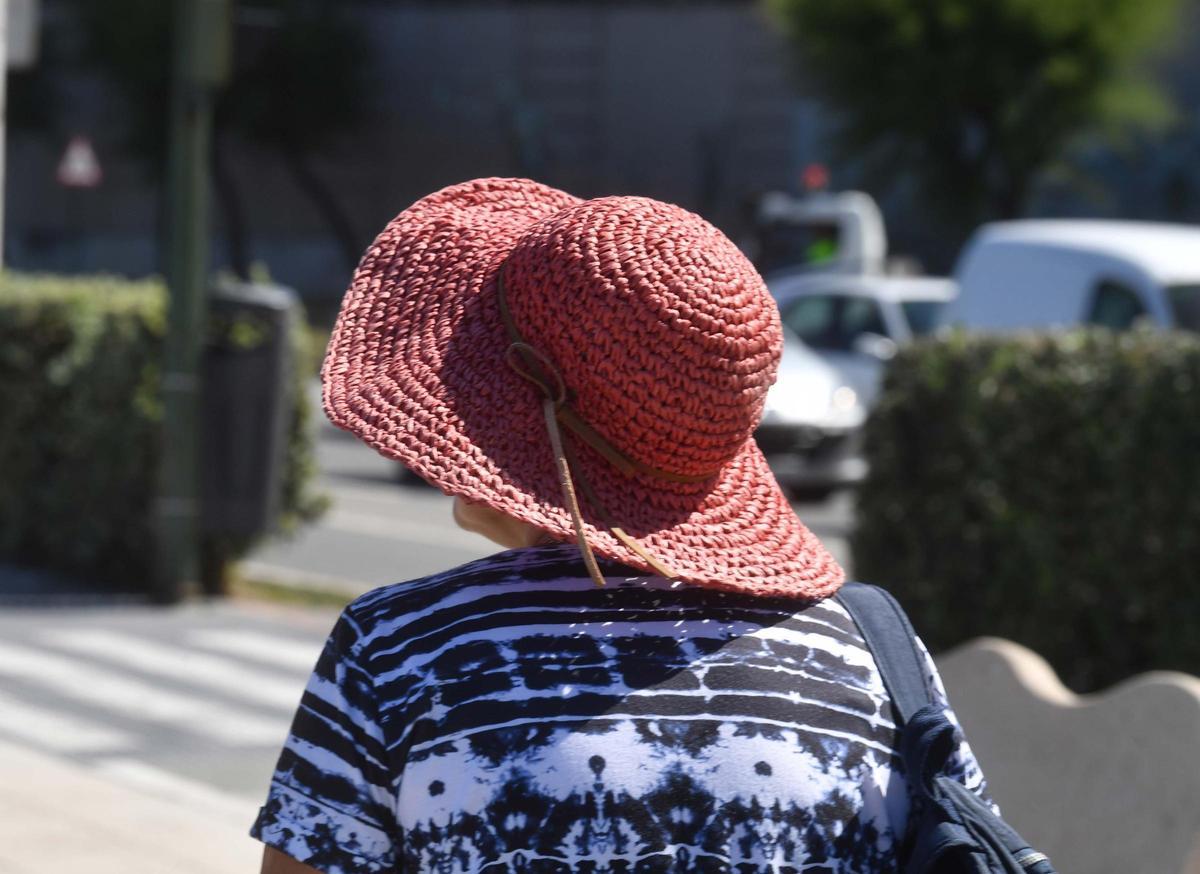 Una mujer con sombrero se protege del sol.
