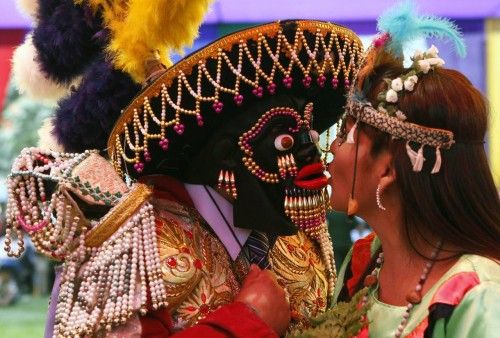 A couple wearing traditional costumes kiss during a mass wedding ceremony, in the district of Comas in Lima