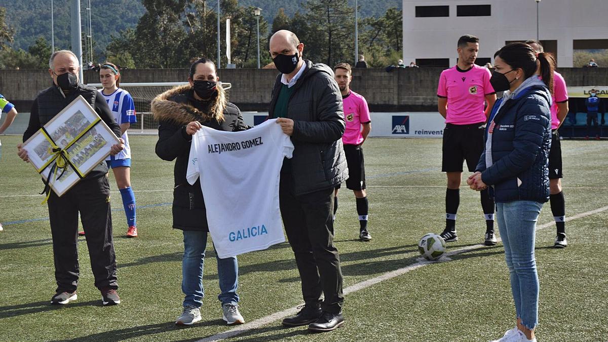 Homenaje a Alejandro Gómez antes del partido. Homenaje previo y minuto de silencio dedicado al olímpico vigués Alejandro Gómez, que fue preparador físico del club. Asistió la alcaldesa de Mos, Nidia Arévalo, el presidente de la RFEF, Rafael Louzán y su homónimo de la UD Mos, Pablo Alonso. Ambos, así como la capitana del Mos B, Jimena, hicieron entrega de diversos recuerdos a la viuda de Gómez Cabral, Paula Hernández. Después, se guardó un minuto de silencio en memoria del atleta olímpico.  | CONCELLO DE MOS