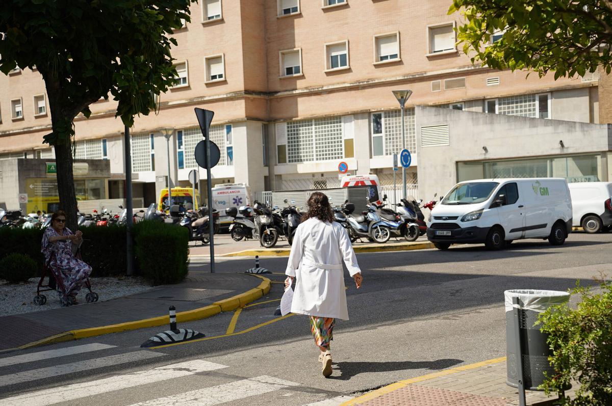 Una profesional sanitaria con bata blanca (médica) cruza uno de los accesos al Hospital Universitario Virgen del Rocío, en Sevilla