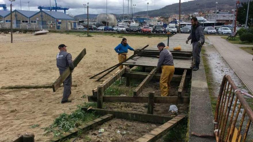 Operarios de la empresa contratada por Portos retiran el paseo de madera de Banda do Río. // G.N.