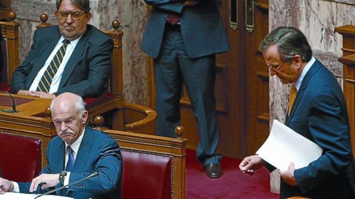 El jefe de la oposición, Antonis Samarás (derecha), abandona el estrado mientras Papandreu revisa papeles.