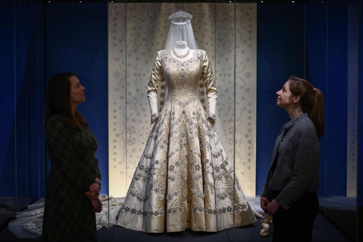 Miembros del personal del Royal Collection Trust posan junto al 'Vestido de novia, velo y cola de la princesa Isabel' de 1947, durante una presentación a los medios de la exposición 'Reina Isabel II: Su vida con estilo'.