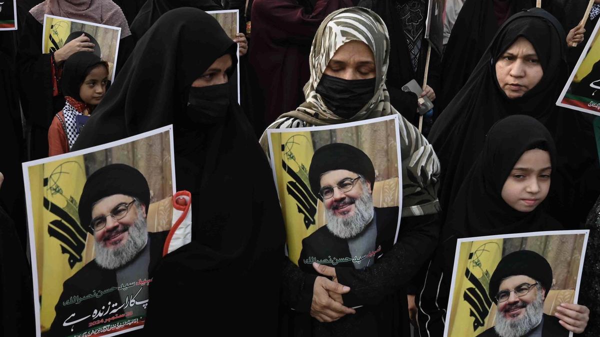 Varias personas sostienen fotos del difunto líder de Hezbolá Hassan Nasrallah.