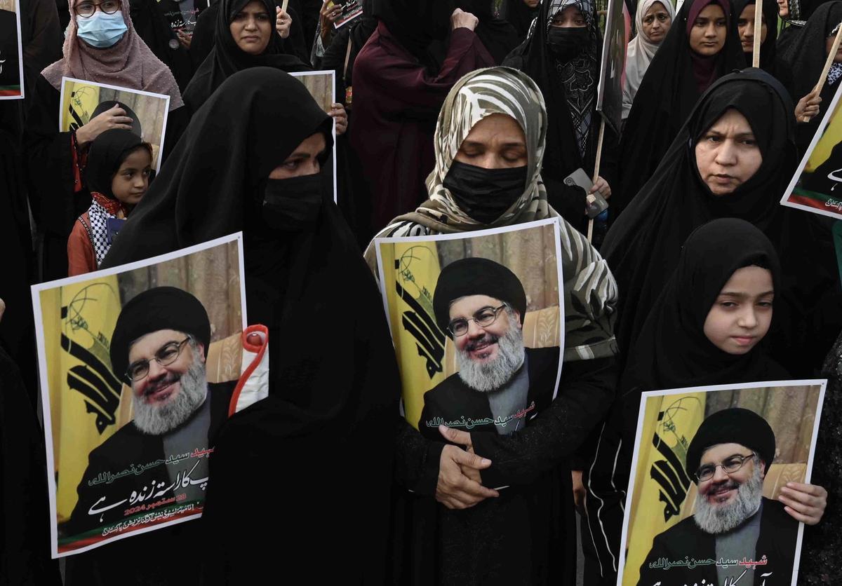 Varias personas sostienen fotos del difunto líder de Hezbolá Hassan Nasrallah.