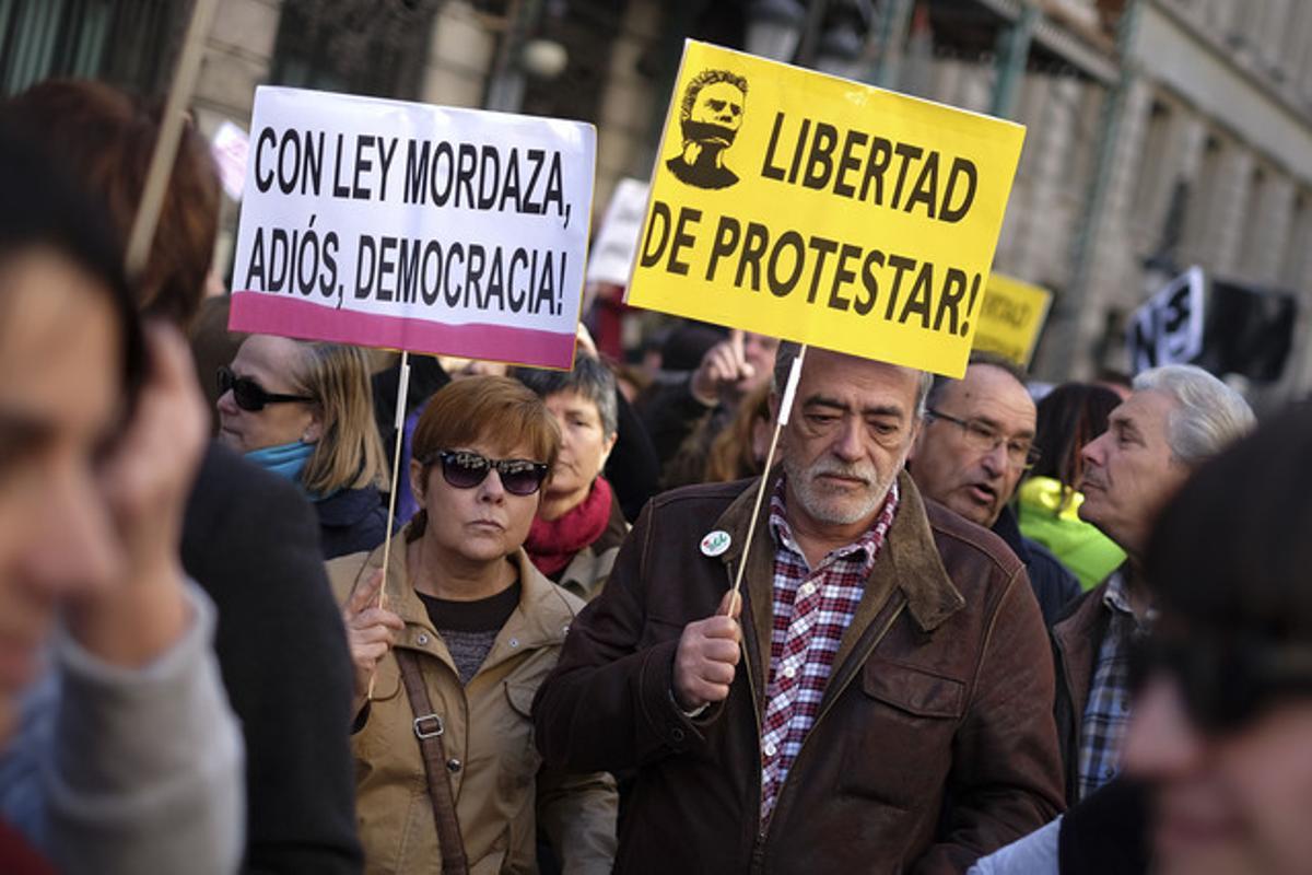 Dos ciutadans amb pancartes en contra de la nova llei de seguretat ciutadana.