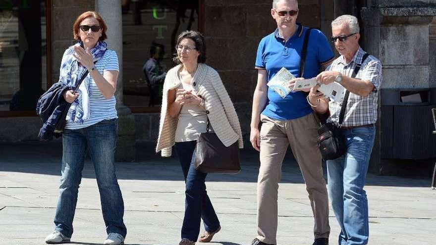 Cuatro visitantes por la plaza de A Ferrería.  // Rafa Vázquez