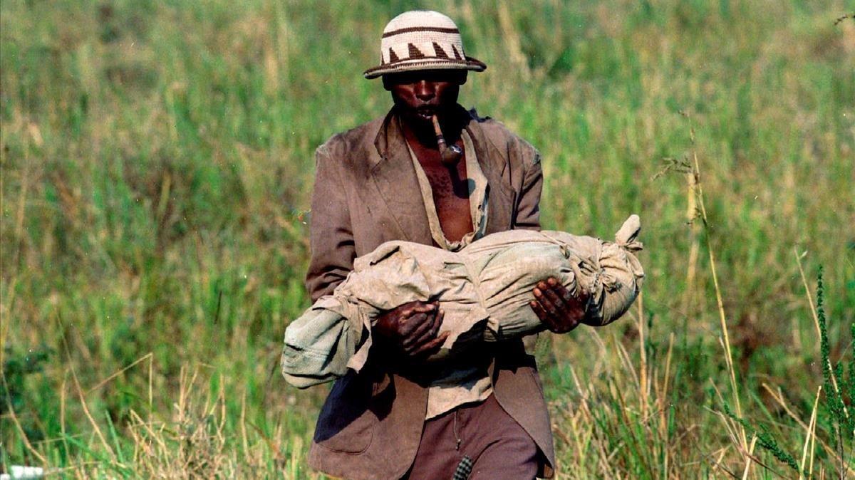 Un refugiado ruandés traslada a una fosa común el cuerpo de su bebé, que murió de cólera.