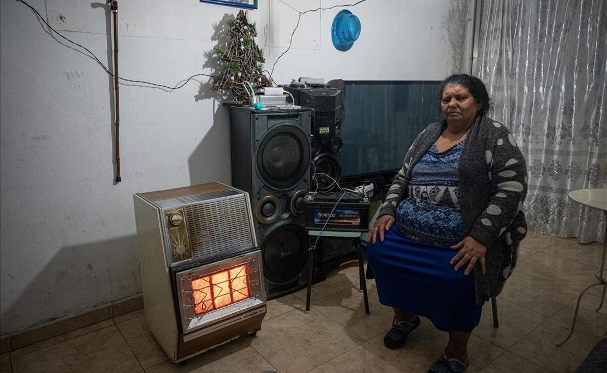 Una vecina muestra como sus hijos le han puesto una batería para poder tener luz.